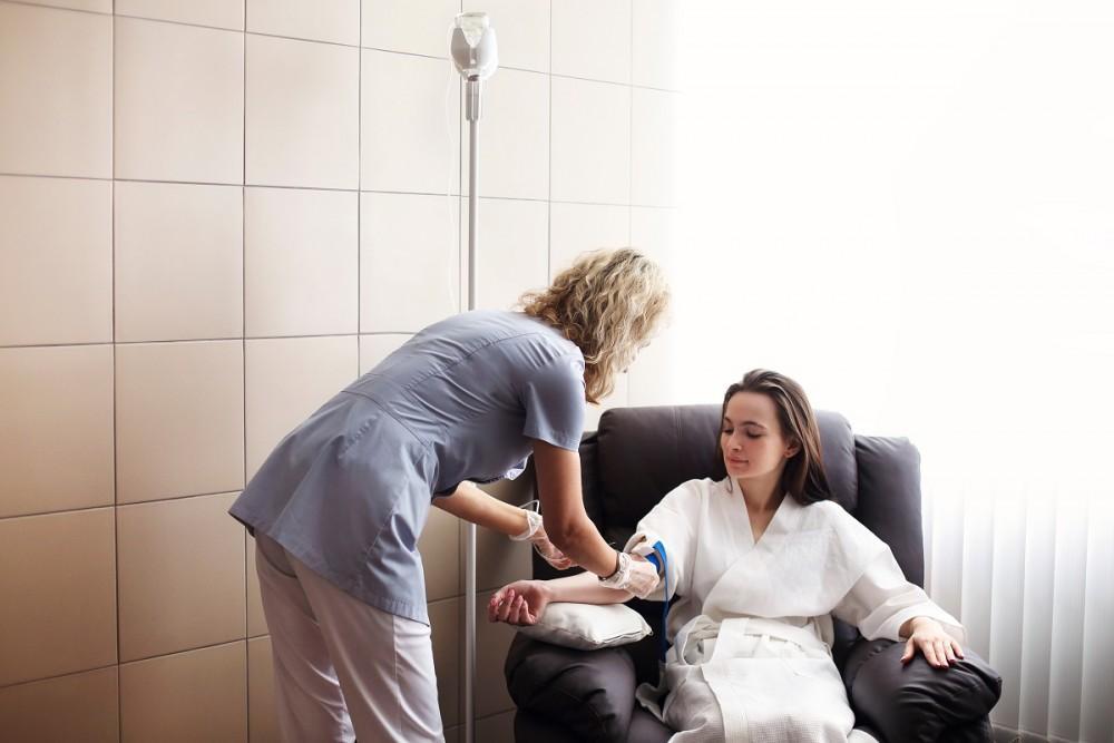 A woman receiving ketamine therapy session with a nurse standing beside her for providing assistance