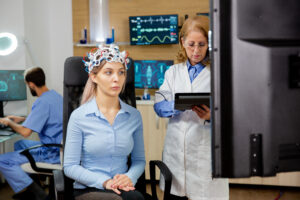 Woman undergoing QEEG Brain Mapping and Neurofeedback Therapy while a doctor monitors brainwave activity in a mental health clinic | Mind Brain Institute