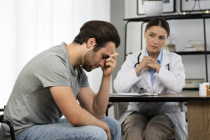 Man struggling with treatment-resistant anxiety during a doctor’s consultation, exploring QEEG Brain Mapping and Neurofeedback Therapy as an alternative approach for anxiety and mental health treatment. | Mind Brain Institute