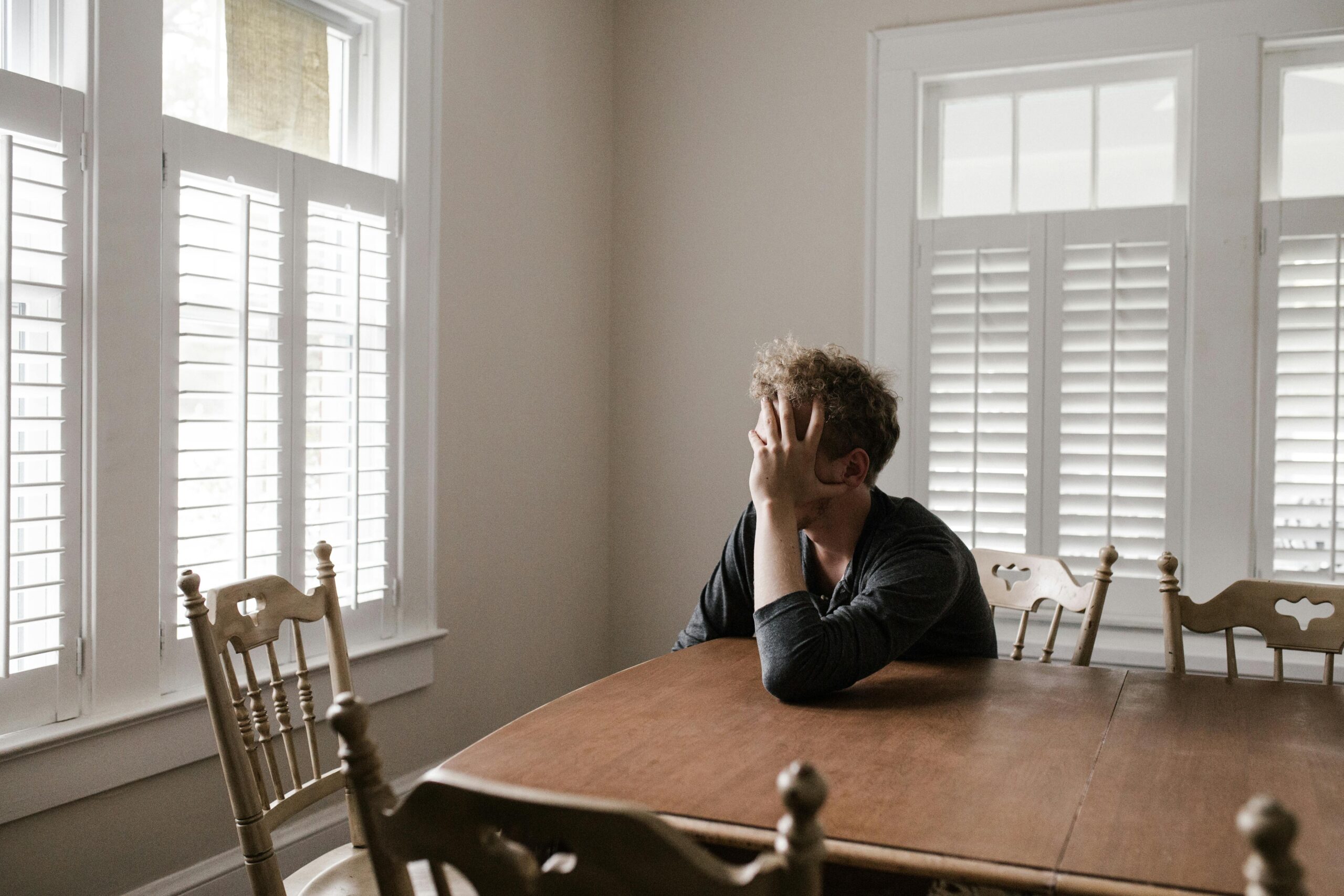 A man can be seen sitting depressed in a corner seat at the table looking outside the window