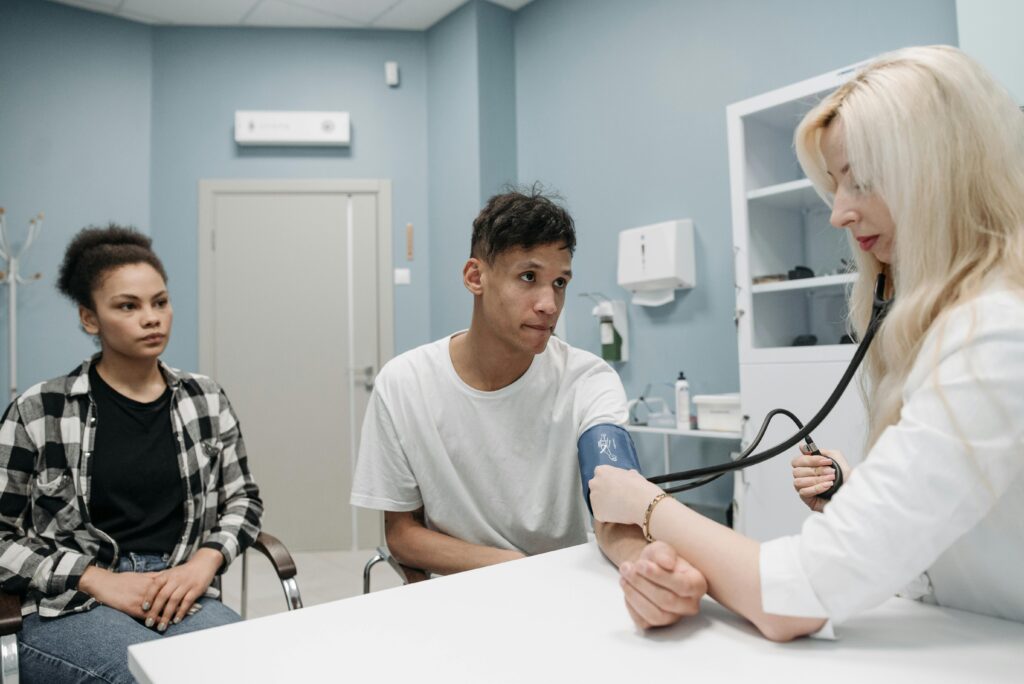 A man and a woman can be seen consulting a doctor and the doctor can be seen testing the arm of the man