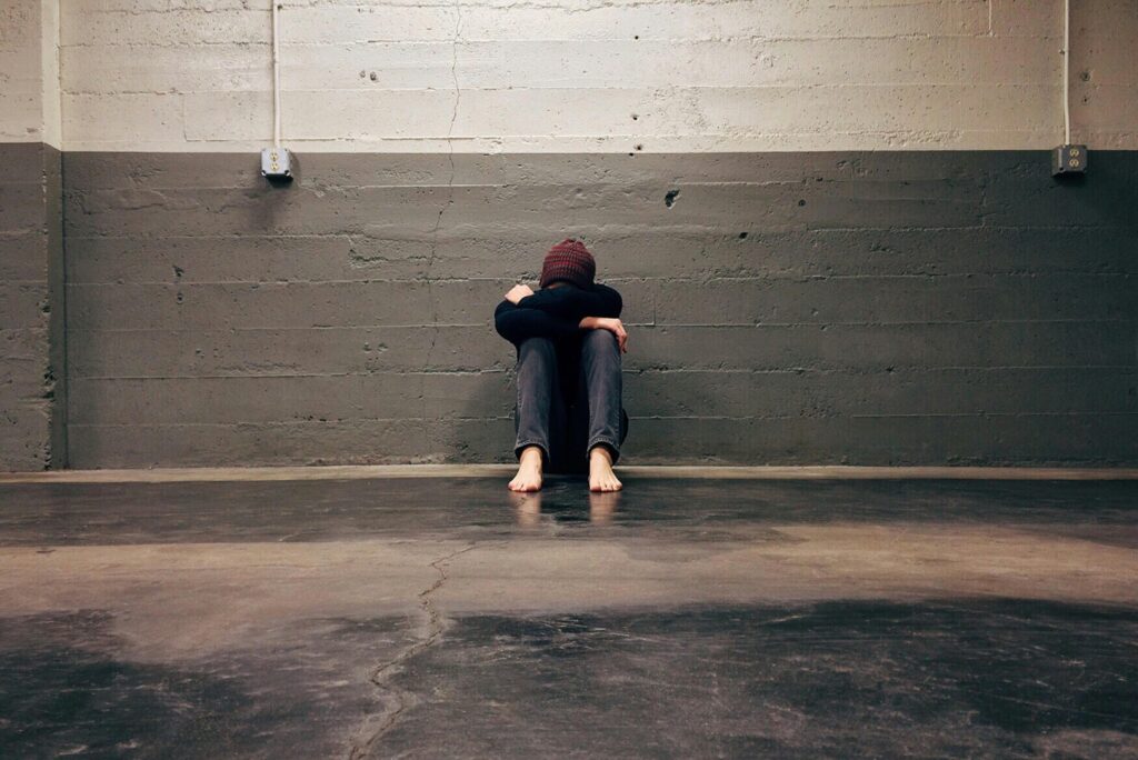 An individual is sitting alone at the floor of an empty room