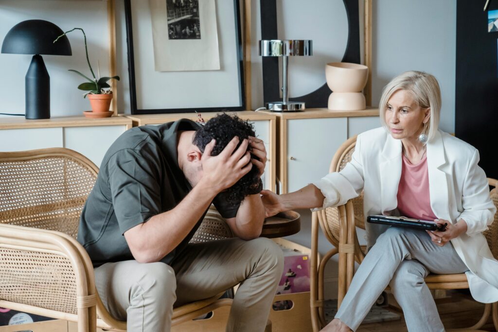 A doctor can be seen helping a person with some kind of counseling and the person and the doctor are sitting across each other on chair