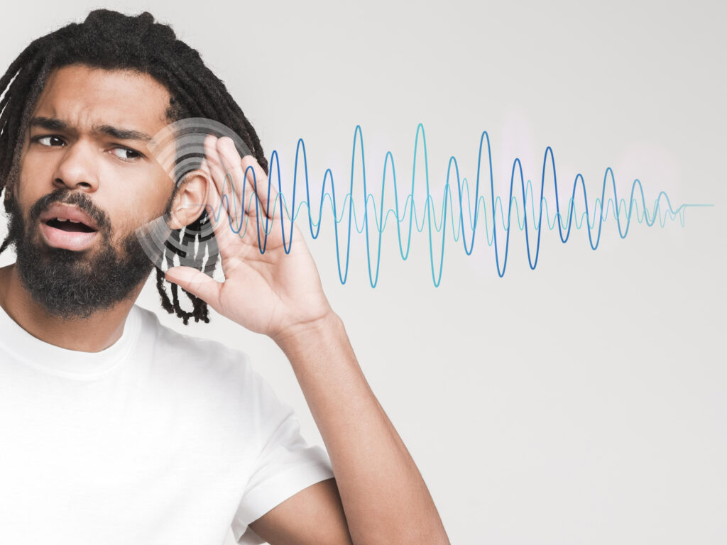 A man can be seen trying to hear something with waves like figure can be seen beside his ear symbolising the direct current stimulation technique