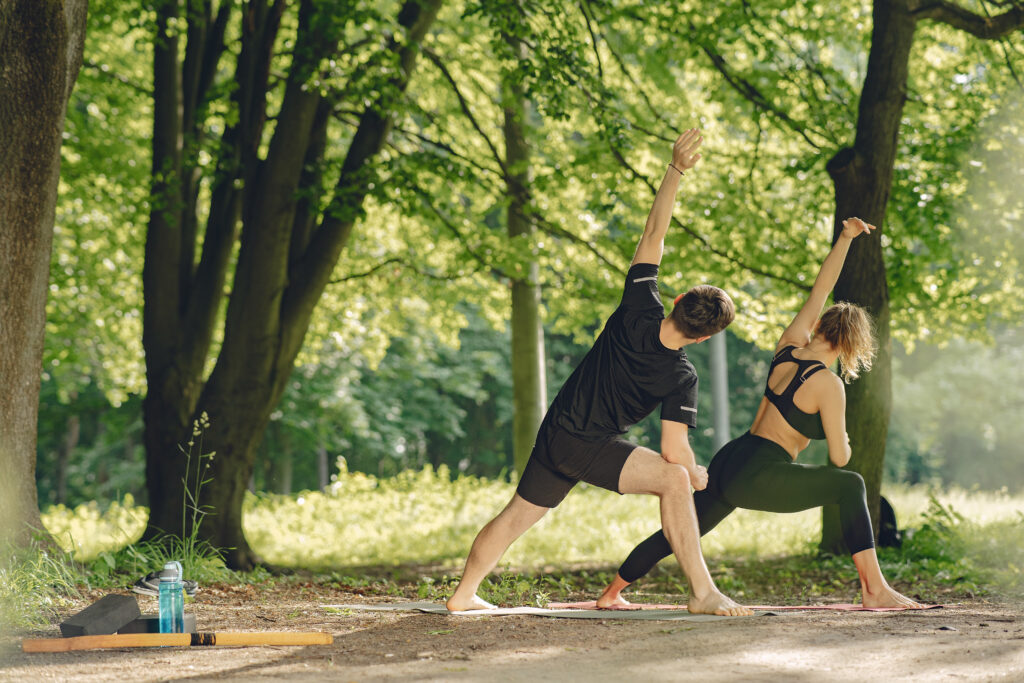 A man and woman can be seen doing a yoga session in a park 