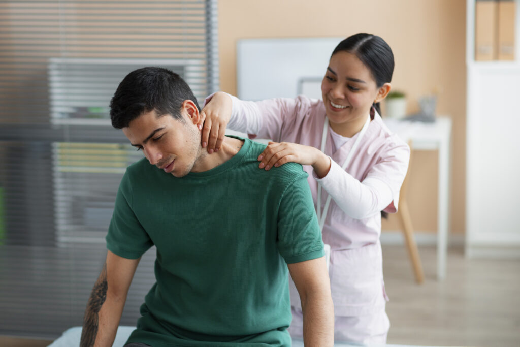 A woman therapist can be seen helping a man with his shoulders in a therepeutic way