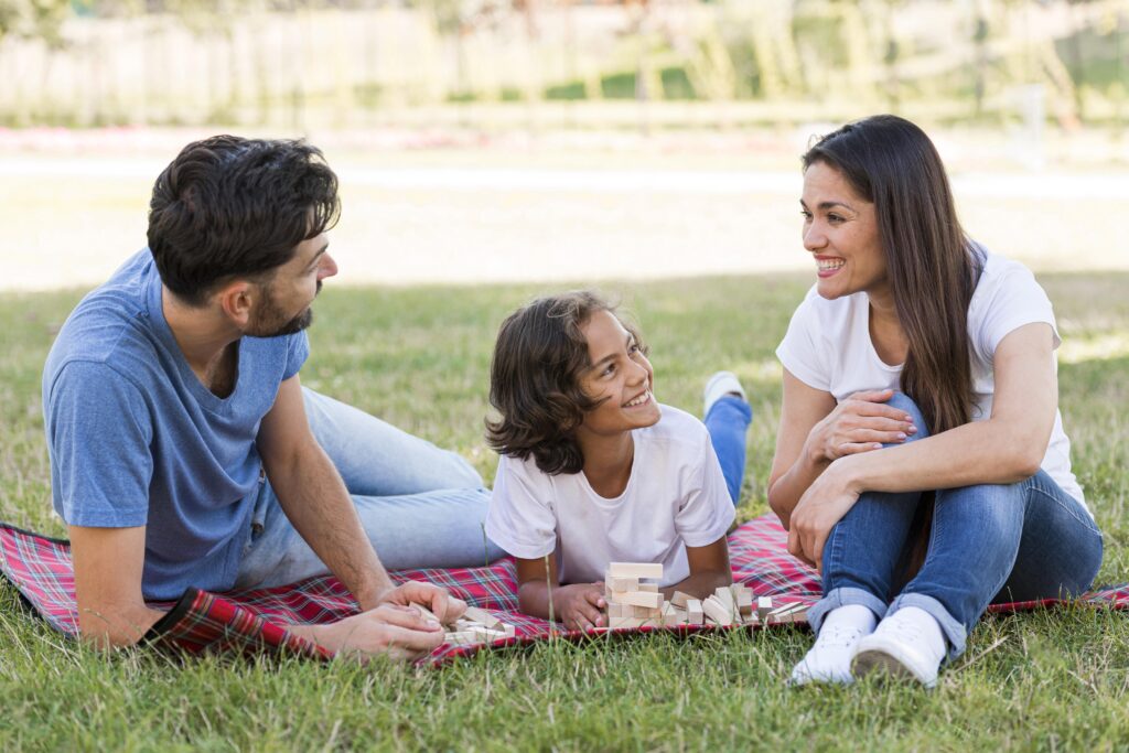 A man, woman and a kid can be seen enjoying in a field that looks like a picnic